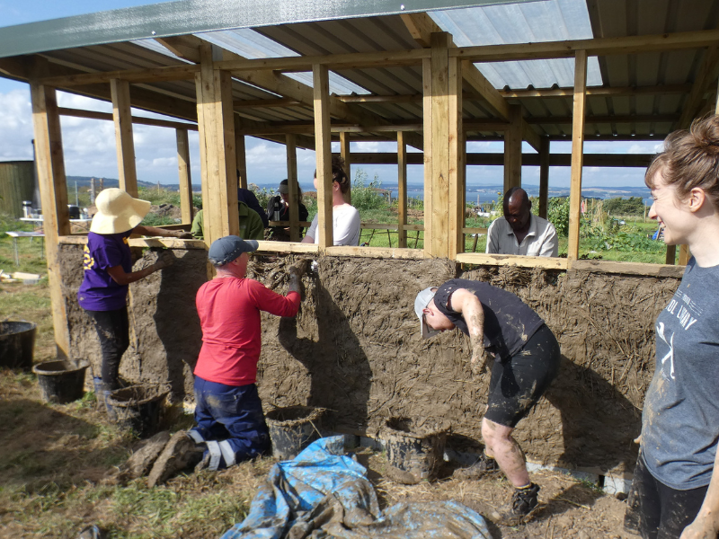 A group work on adding clay to the lower half of the building