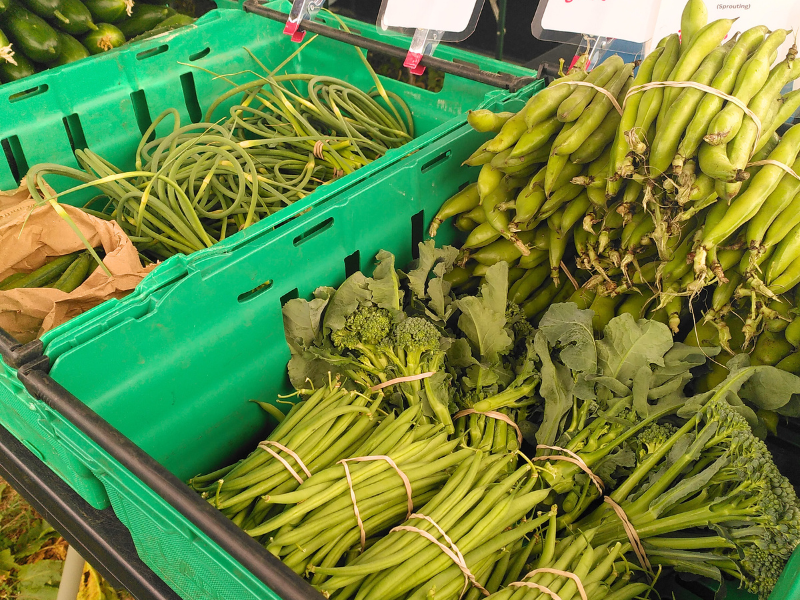 A mix of fresh green veg in crates on display at the stall