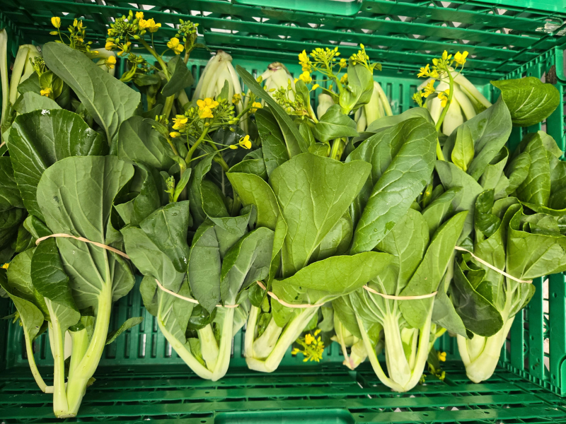 Crate of bright green veg with yellow flowers